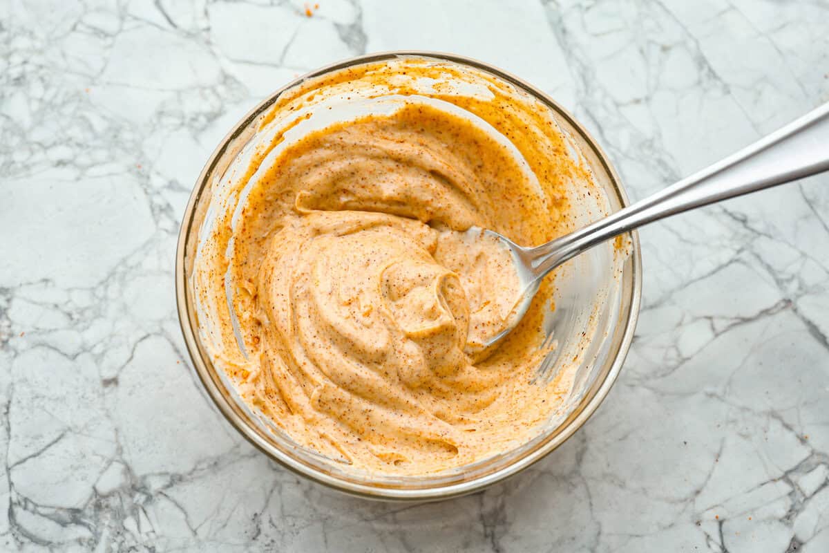 Homemade Sweet Corn Tamale Cakes are an explosion of delicious flavor in every bite! With this easy recipe you can bring this Cheesecake Factory favorite right to your own kitchen. Add the signature topping to really take these to the next level! Overhead shot of mayonnaise and southwest seasoning mixed together in a small bowl.