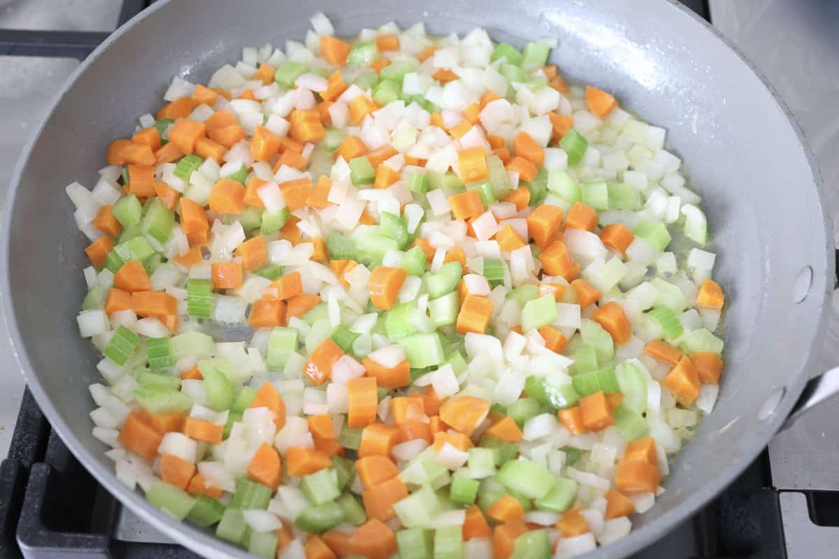 Chicken pot pie casserole is a fun twist on the classic pot pie. It's made with buttery biscuit dough, tender chicken, crunchy veggies, and the most delicious creamy sauce loaded with incredible seasoning. Comfort food at its finest! Overhead shot of veggies sautéing in a skillet.