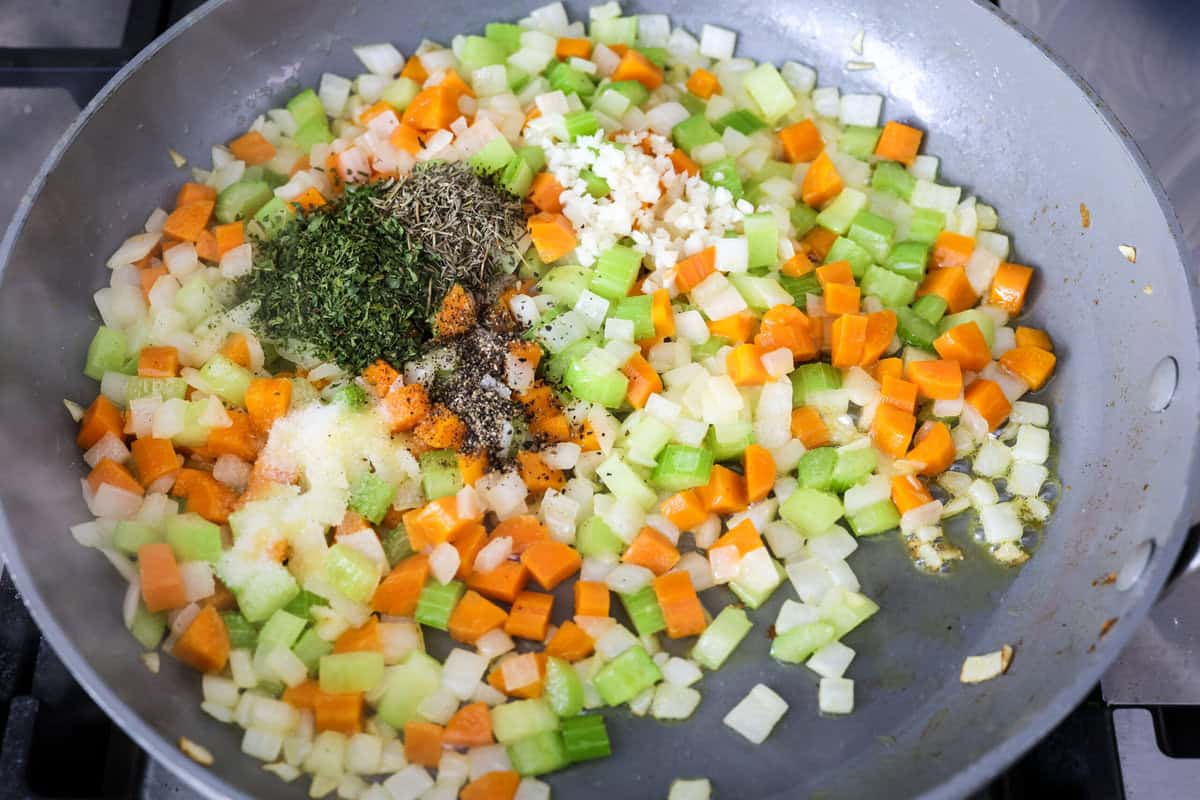 Chicken pot pie casserole is a fun twist on the classic pot pie. It's made with buttery biscuit dough, tender chicken, crunchy veggies, and the most delicious creamy sauce loaded with incredible seasoning. Comfort food at its finest! Overhead shot of cooked veggies with seasonings on top.
