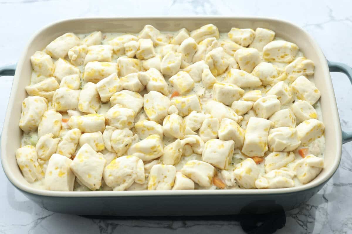 Chicken pot pie casserole is a fun twist on the classic pot pie. It's made with buttery biscuit dough, tender chicken, crunchy veggies, and the most delicious creamy sauce loaded with incredible seasoning. Comfort food at its finest! Angle shot of chicken pot pie casserole with biscuit pieces on top.