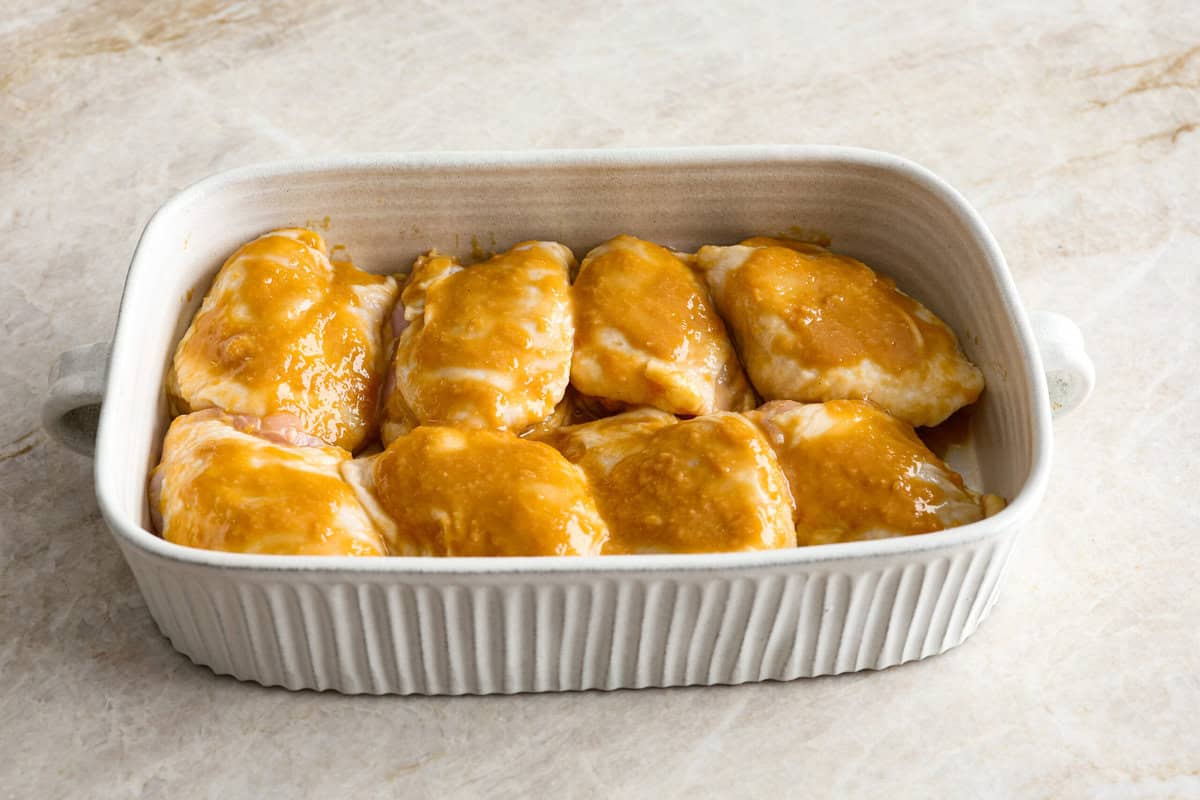 Miso chicken is super delicious and perfect for fans of bold Asian flavor. The skin crisps up, the meat stays juicy and tender, and the glaze caramelizes, creating a savory sauce perfect for drizzling over rice. Angle shot of marinated chicken in a baking dish.