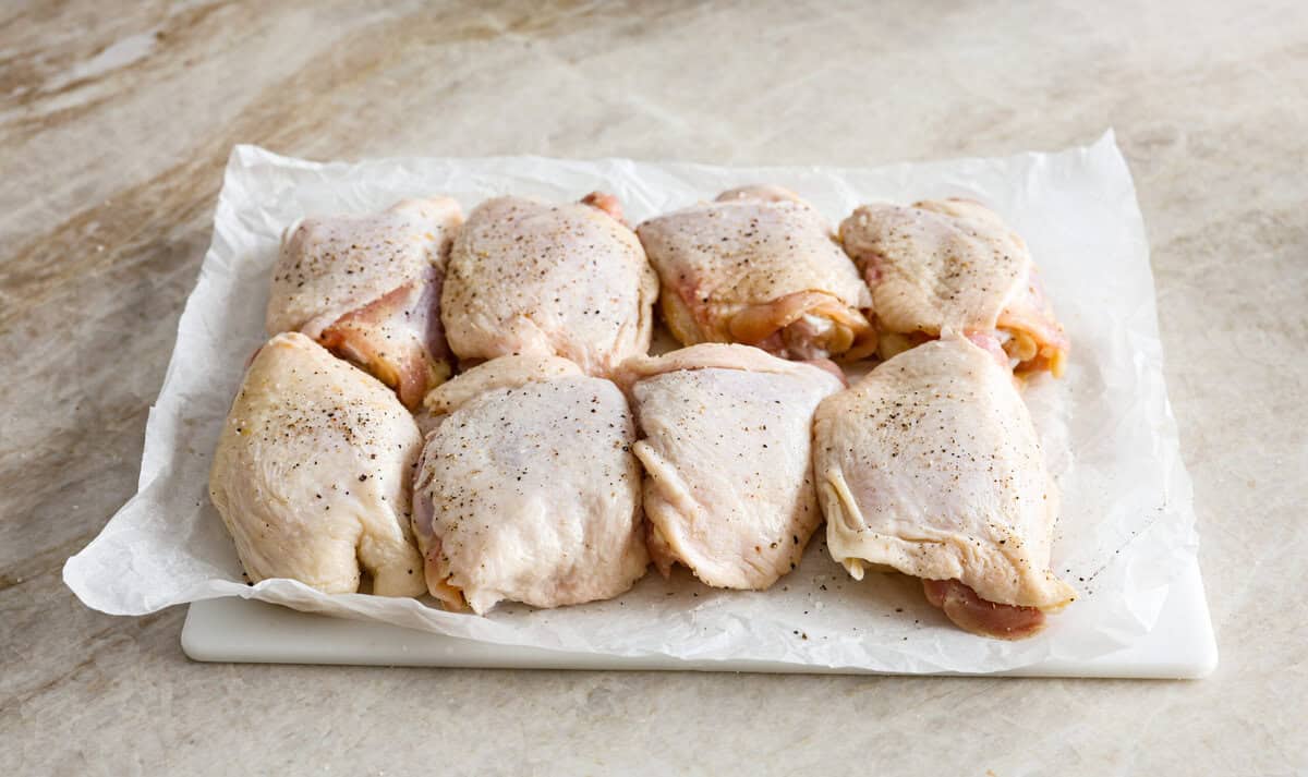 This incredibly tasty Coca-Cola chicken thigh recipe can be on the table in 40 minutes. The succulent sauce is a combination of savory soy sauce, Worcestershire, garlic, ketchup, and, of course, Coca-Cola. You've never had more flavorful chicken thighs than these! Angle shot of chicken thighs seasoned with salt and pepper.