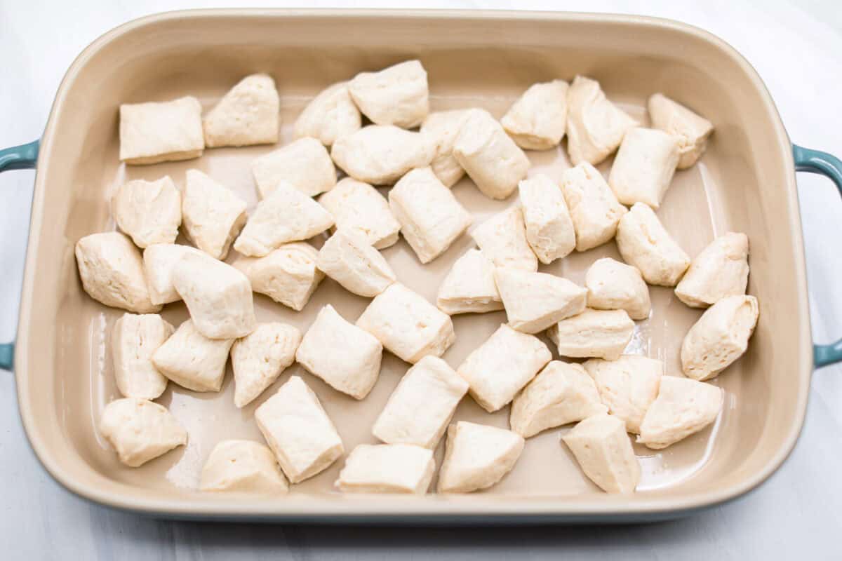 Overhead shot of biscuit pieces spread out in the bottom of a baking dish. 