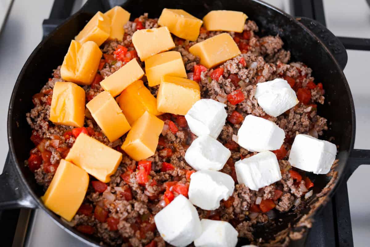 Overhead shot of beef mixture with Velveeta and cream cheese on top. 