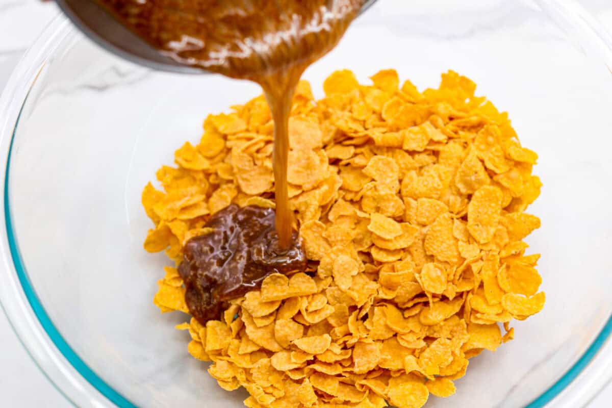 The photo from above shows someone pouring a mixture of boiled butter and sugar into a bowl filled with cornflakes. 