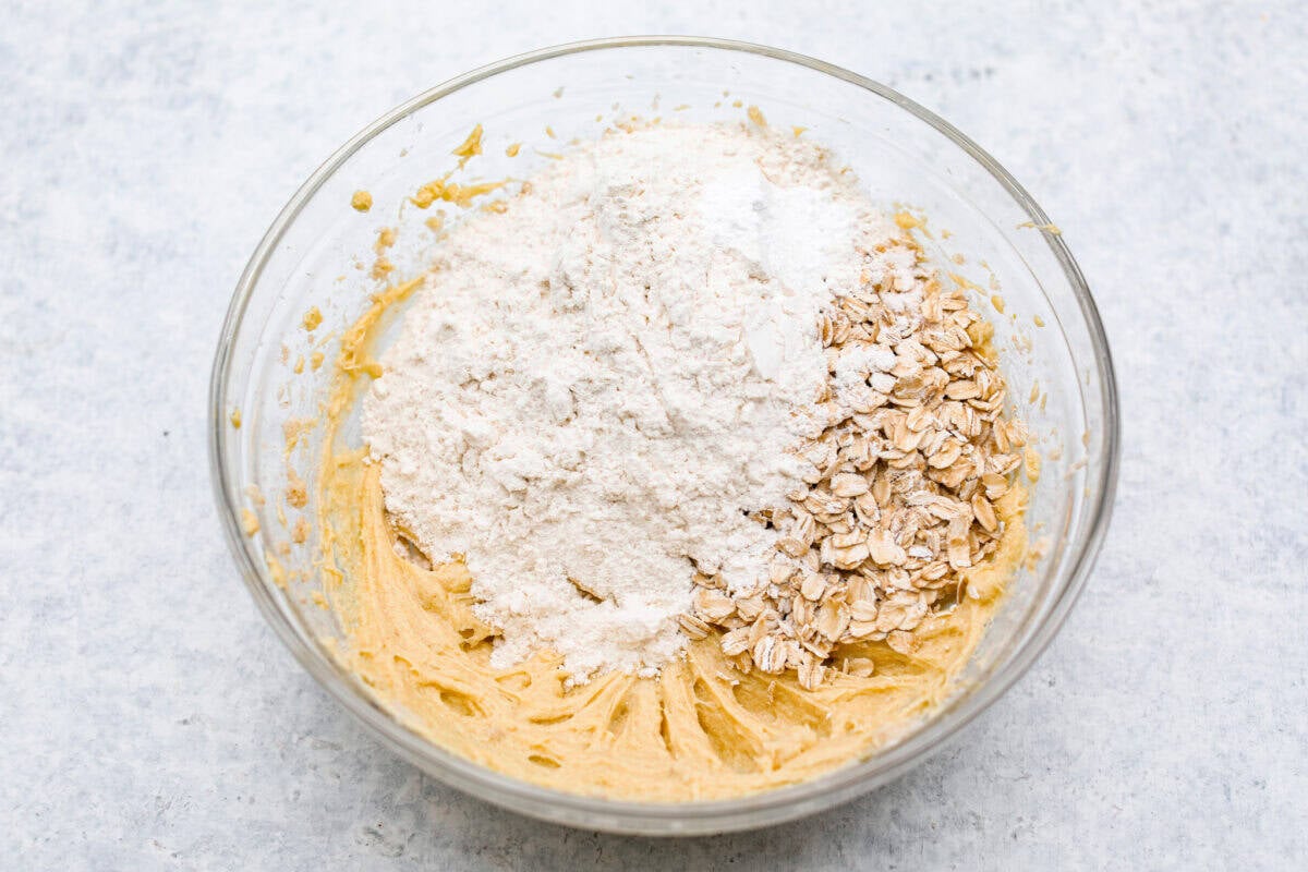 Overhead shot of butter mixture with oats, flour, baking powder,  baking soda and salt on top. 