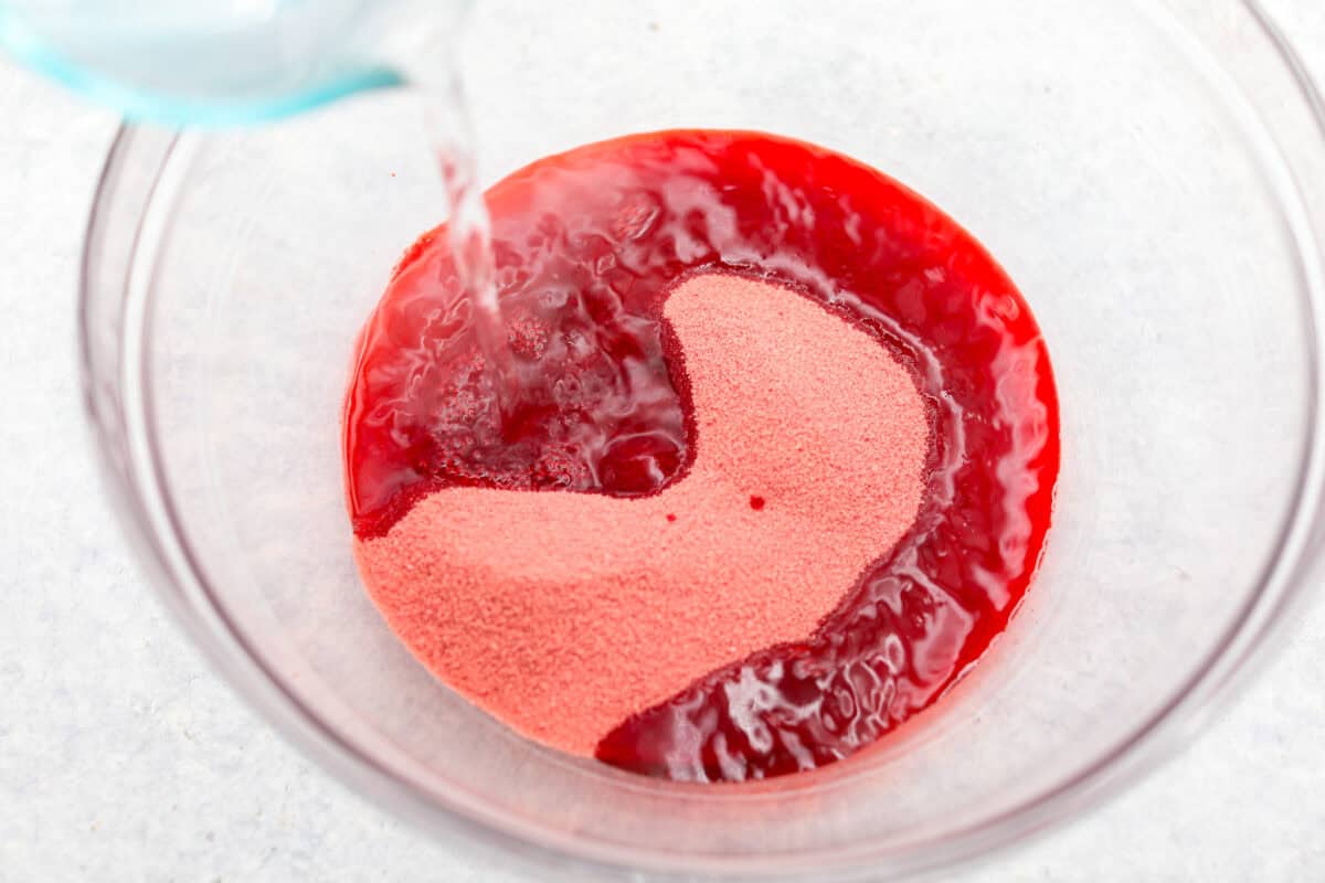 Overhead shot of boiling water being poured into jello mix. 