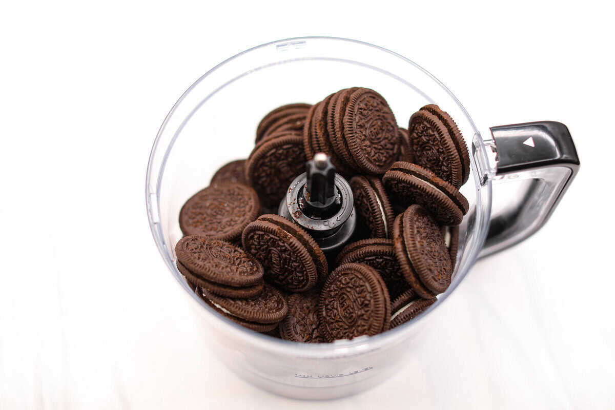German Chocolate Cheesecake is a rich and impressive dessert! It has an Oreo cookie crust, a chocolate cheesecake filling, and a classic German chocolate topping to finish it off! The gooey coconut pecan topping takes this cheesecake to the next level! First photo of Oreo cookies in a food processor.
