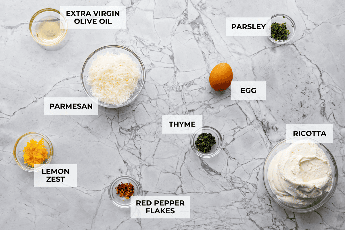 Irresistible Baked Ricotta Dip is the perfect party appetizer! It takes just minutes to combine creamy ricotta cheese with parmesan, fresh herbs, and lemon zest. Then, bake until bubbly and delicious, and get ready for an explosion of flavor! Overhead shot of labeled ingredients.