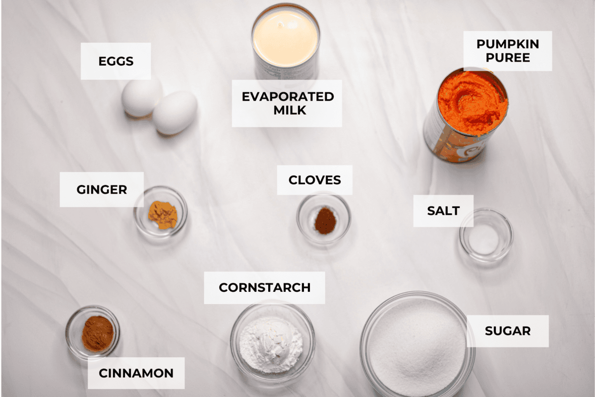 Crustless pumpkin pie has rich spices, creamy pumpkin, and a perfectly smooth texture. The custard holds its shape beautifully. Whether you're keeping things simple or exploring a gluten-free option, this pie gives all the nostalgic vibes of the classic. Overhead shot of labeled ingredients.