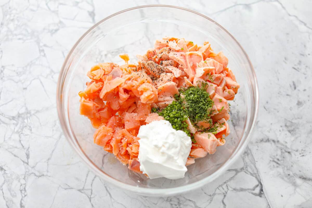 Overhead shot of flaked and smoked salmon mixed with herbs, lemon juice and sour cream. 