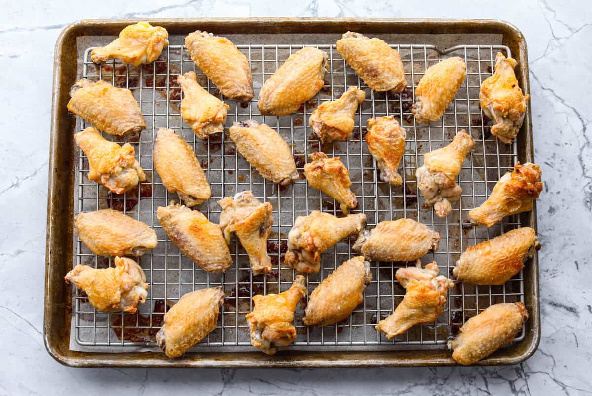 These sweet and sour wings are the perfect appetizer to serve for your next party, game day, or after-school snack. They are baked to crispy perfection and then doused in a sticky, sweet, and sour sauce. Baked wings on baking rack.