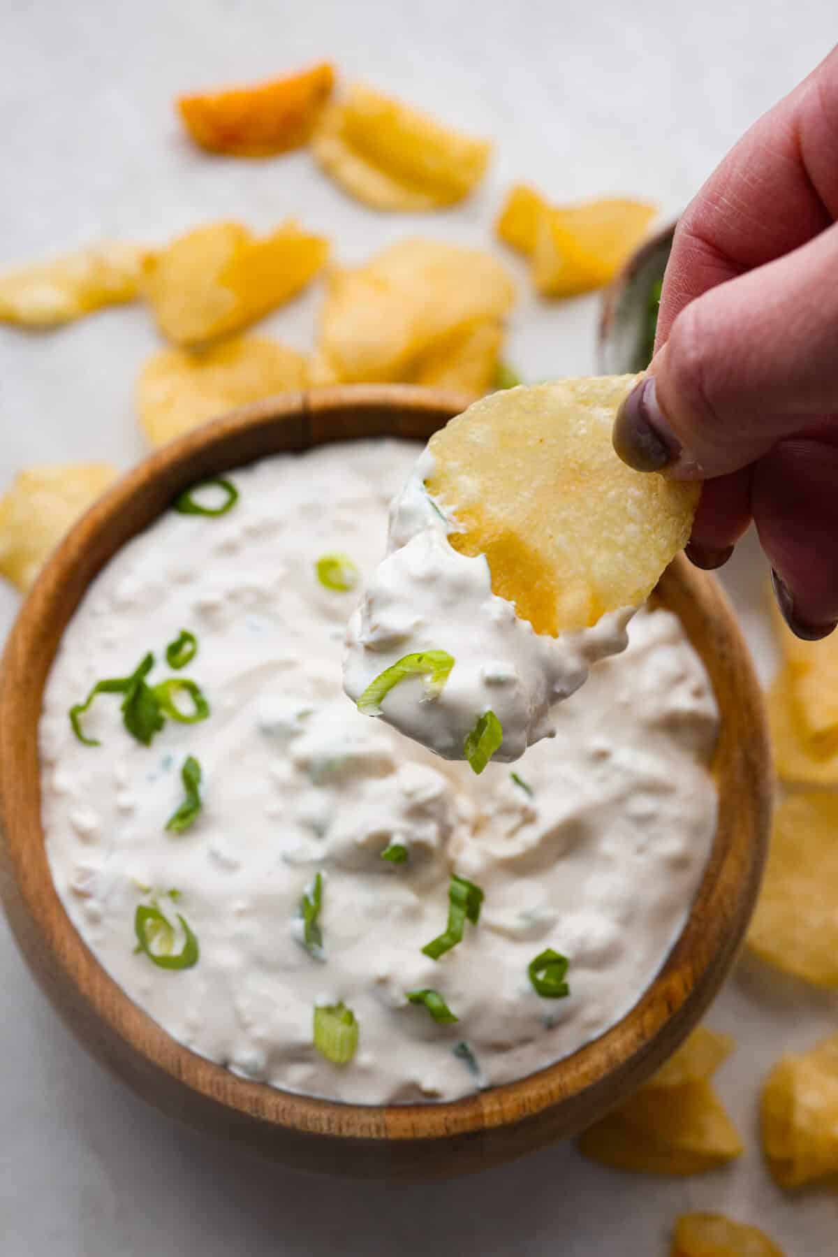 Overhead shot of someone sipping a chip into the clam dip. 