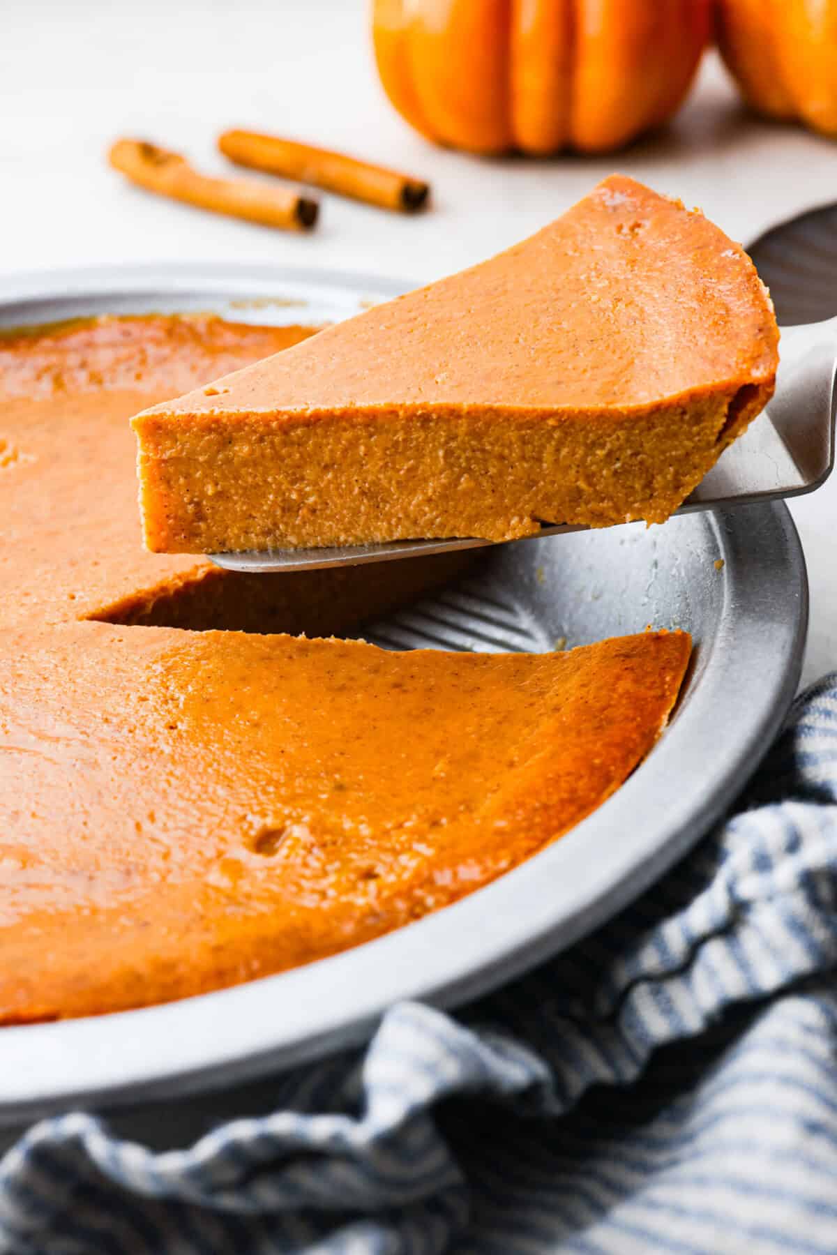 Angle shot of a slice of crustless pumpkin pie being lifted out the pie pan. 