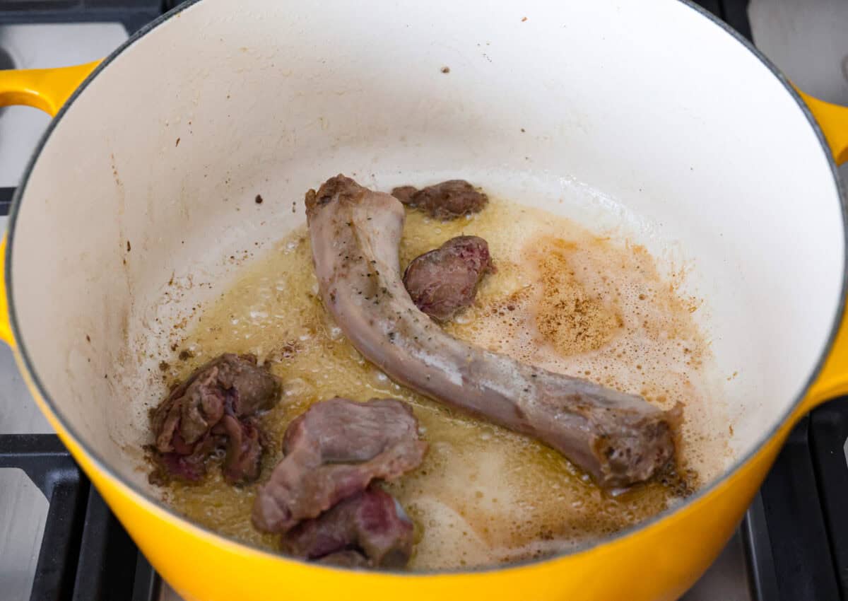 Angle shot of giblets cooking in melted butter in a pan. 