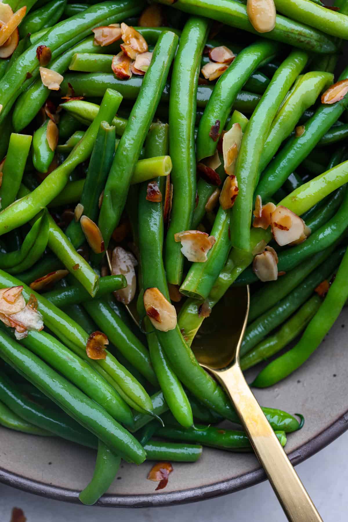 Green Beans Almondine is made with fresh green beans that are sautéed until crisp-tender and then tossed with buttery, toasted almonds. Every bite is filled with nutty richness and a hint of lemon to brighten up the flavors. Close up shot of green beans Almondine.