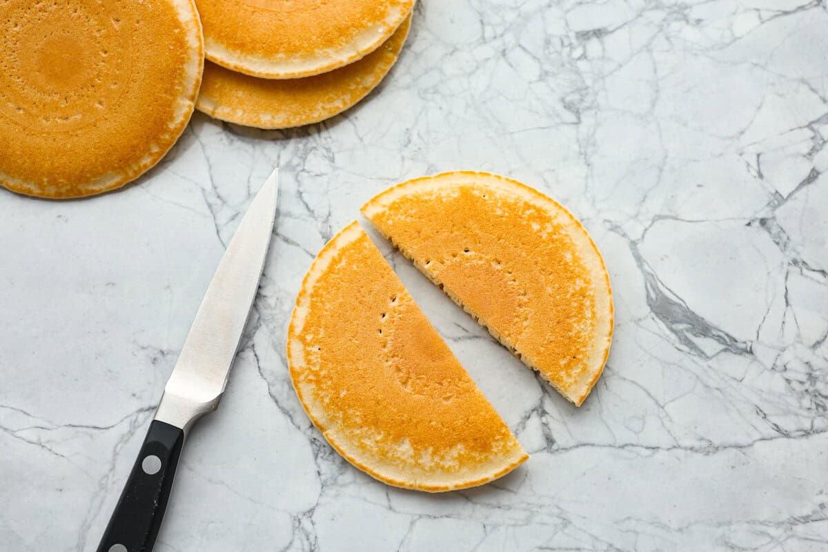 Pancake Casserole is a fun new Christmas or Easter breakfast idea. It has lots of buttery pancakes soaked overnight in a creamy custard, is baked to perfection, and served with your favorite toppings! Overhead shot of a pancake cut in half.