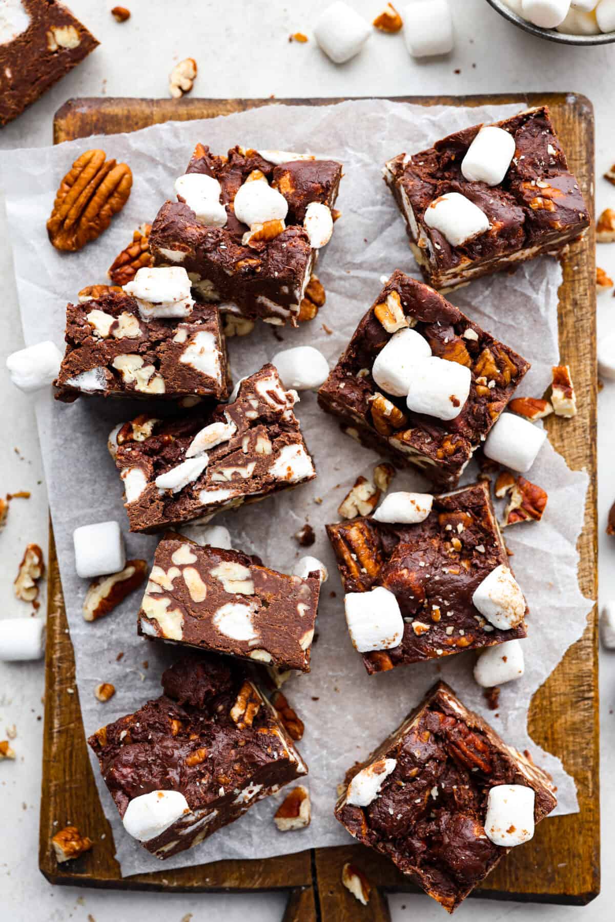 Overhead shot of rocky road bars cut up on parchment paper on a wooden cutting board. 