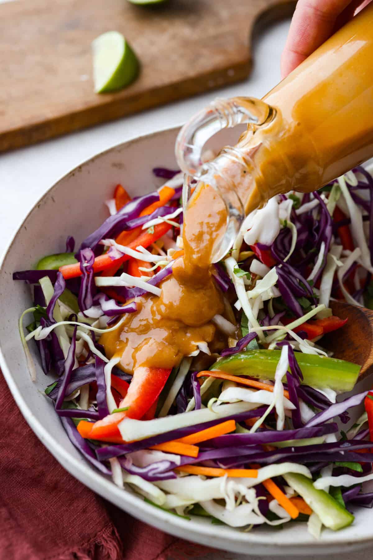 Angle shot of Thai peanut dressing being drizzled over salad.