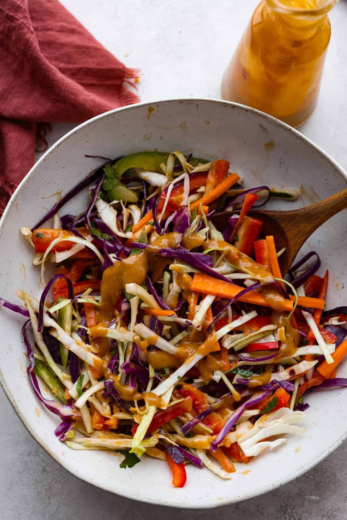 Thai peanut dressing is perfect for drizzling over fresh chopped salads or dipping veggies. It's a creamy mix of peanut butter, soy sauce, lime juice, and sweet chili sauce with a touch of garlic and ginger. It’s nutty and tangy, with the perfect amount of spice. Overhead shot of a Thai salad with Thai peanut dressing drizzled over the top.