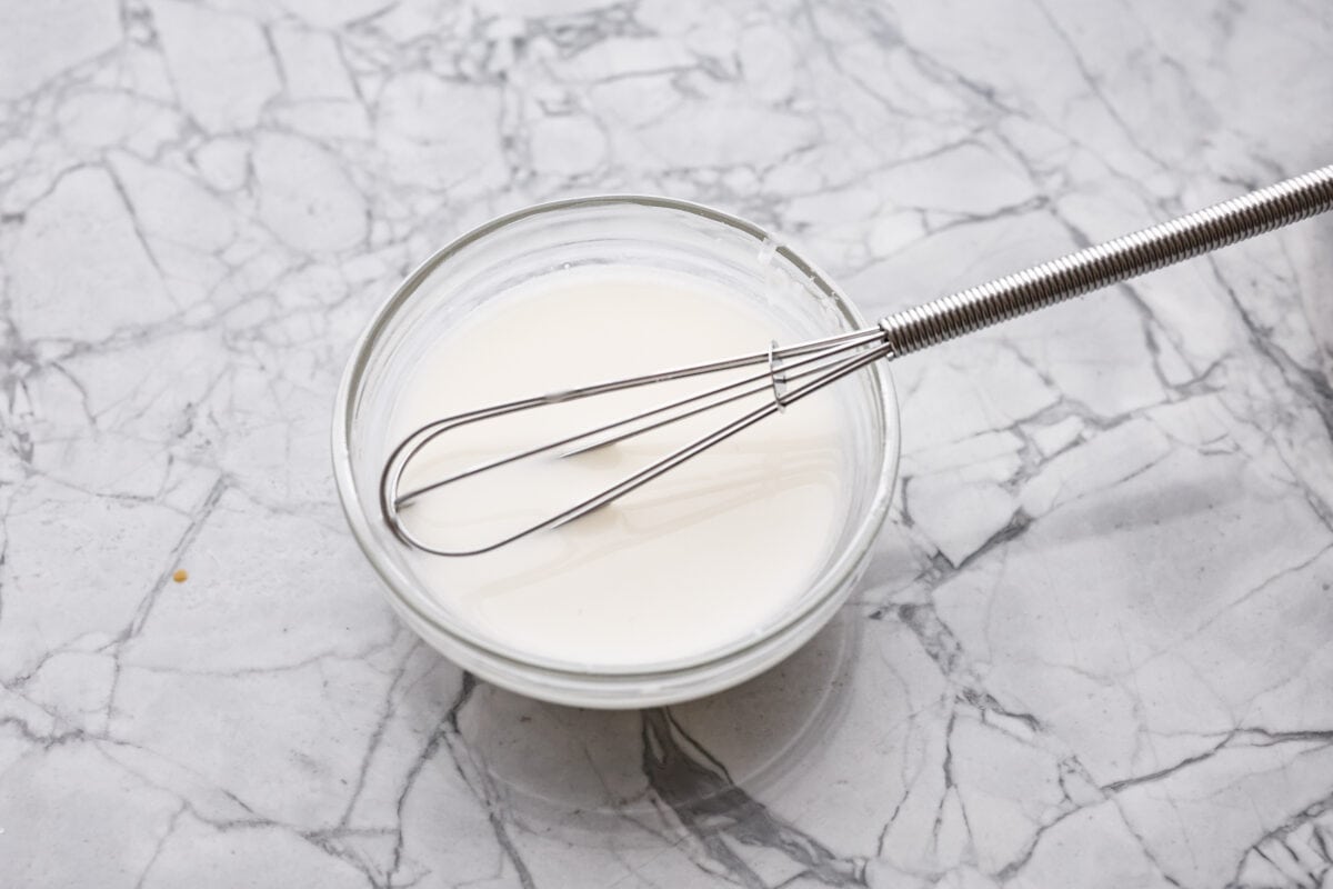 Overhead shot of cornstarch and water whisked together in a bowl. 