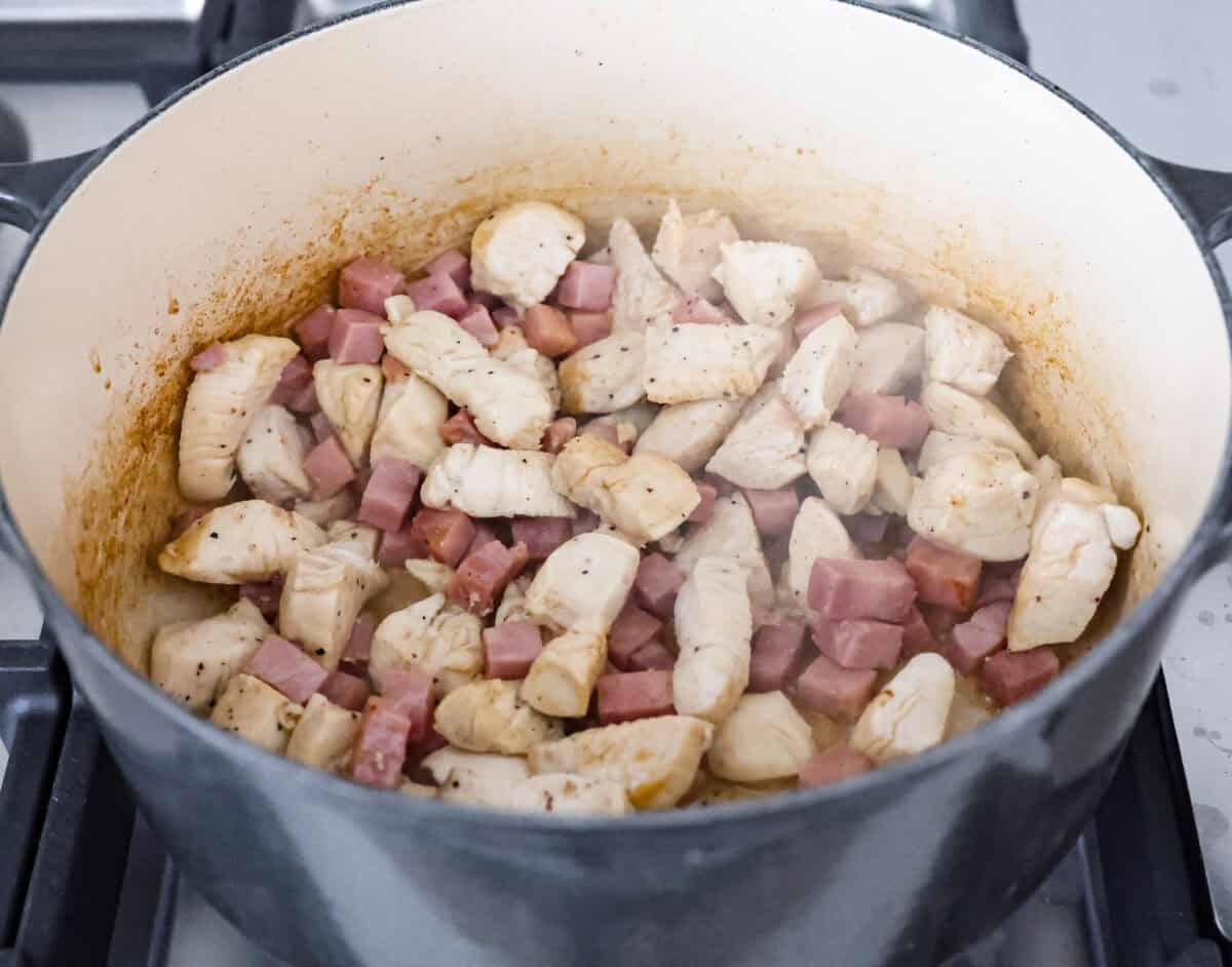 Angle shot of chicken and ham cooking in a pot. 