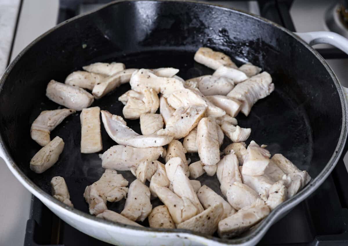 Angle shot of chicken being cooked in a skillet. 