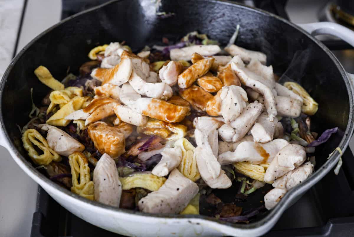 Angle shot of the Moo Shu chicken and eggs added to the cabbage and mushrooms with sauce poured over the top. 