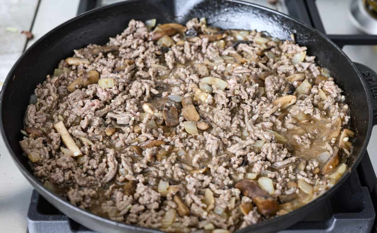 Salisbury Steak casserole is a warm and comforting savory dish. It has a thick beef gravy, tender mushrooms, and seasoned hamburger topped with rich, creamy potatoes. Angle shot of the ground beef mixed into the salisbury steak gravy mixture.