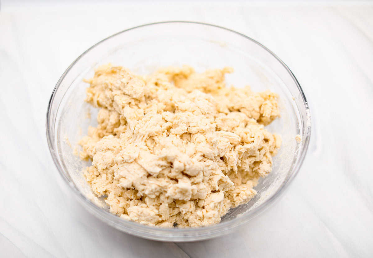 Biscuit Cinnamon Rolls are the most amazing twist on a classic! They are perfectly light, fluffy, and packed with cinnamon. The texture is more flakey and moist than traditional cinnamon rolls! Whether it’s for a cozy weekend breakfast or a holiday brunch, these hit the spot! Angle shot of shredded butter and dry ingredients incorporated.
