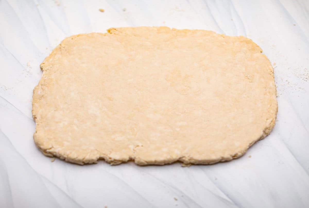 Biscuit Cinnamon Rolls are the most amazing twist on a classic! They are perfectly light, fluffy, and packed with cinnamon. The texture is more flakey and moist than traditional cinnamon rolls! Whether it’s for a cozy weekend breakfast or a holiday brunch, these hit the spot! Overhead shot of biscuit dough rolled out into a rectangle.