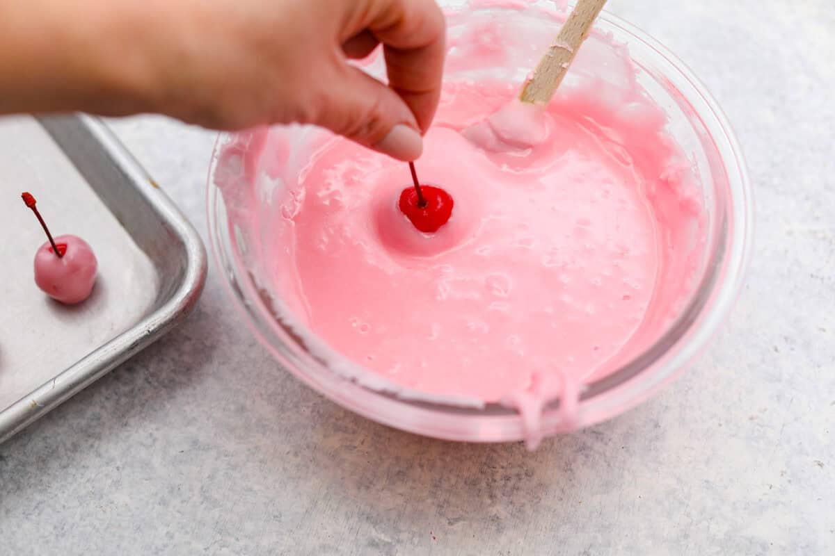 Angel shot of someone dipping cherries into the fondant. 