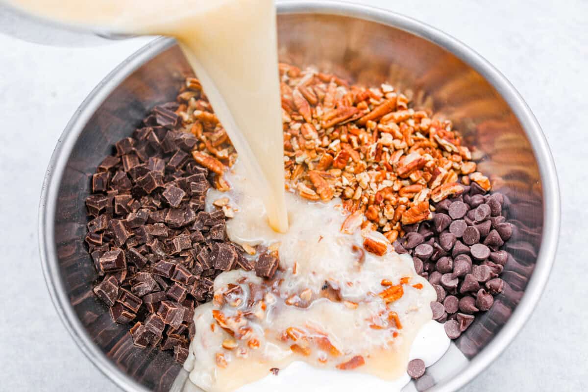 Overhead shot of the warm milk mixture being poured over the chocolate and nuts. 