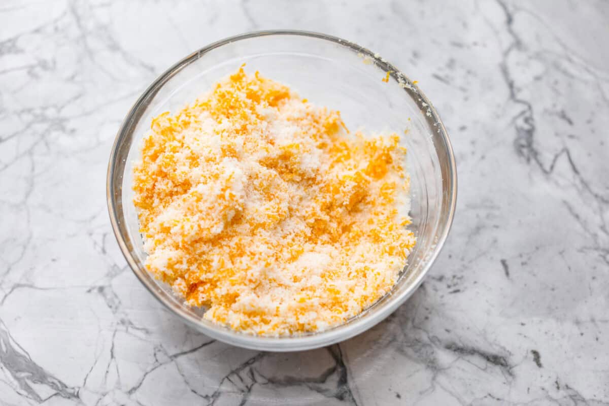 Overhead shot of sugar and orange zest mixed in a bowl. 