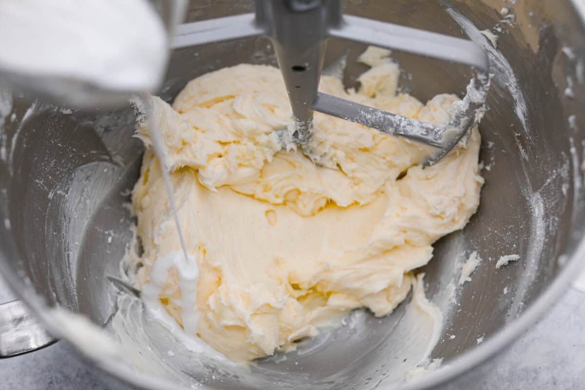 Overhead shot of someone pouring milk into the frosting mixture. 