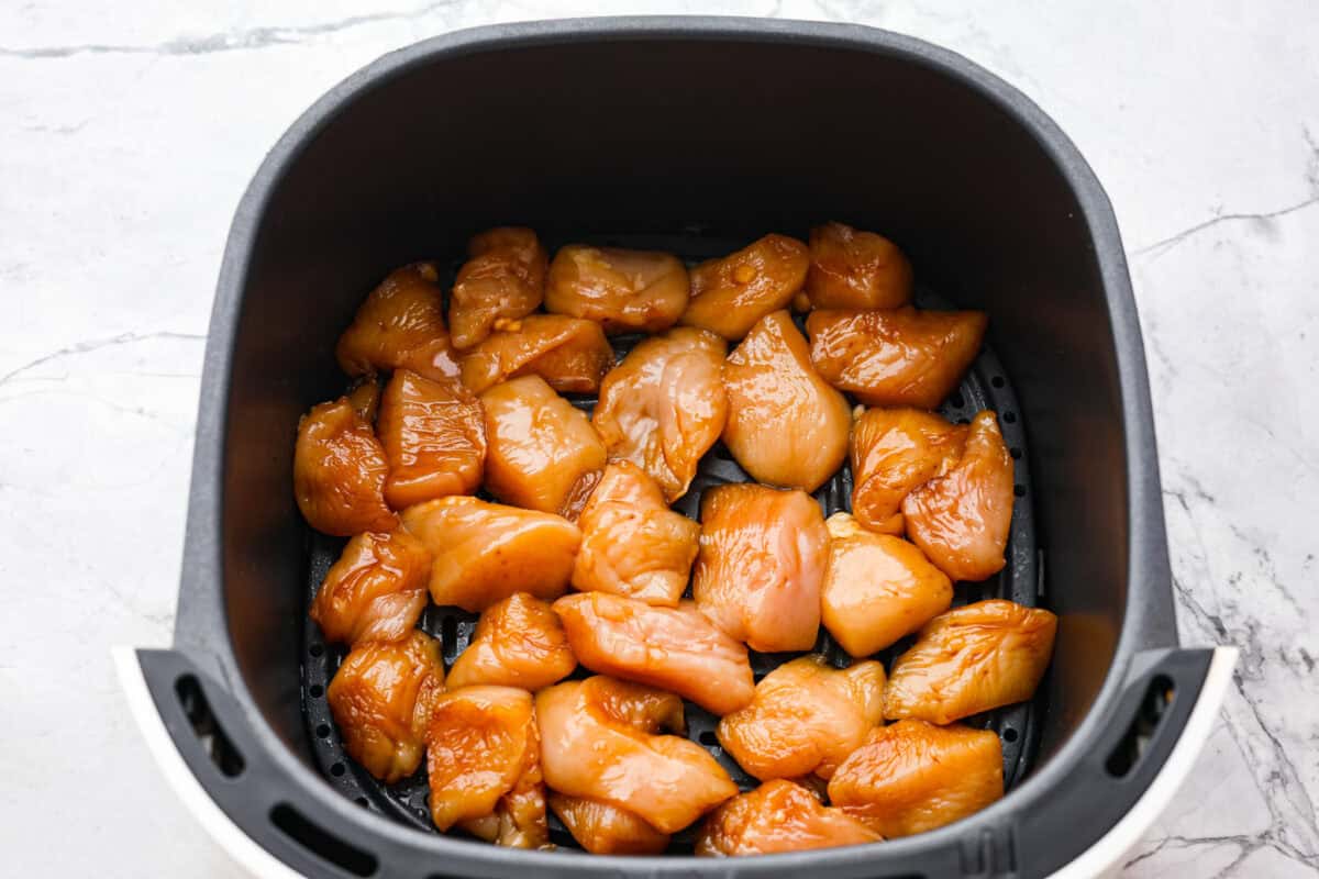 Overhead shot of marinated chicken in the bottom of an air fryer basket. 