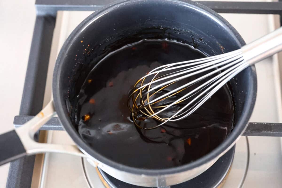 Overhead shot of sauce ingredients being whisked on the stove in a pot. 