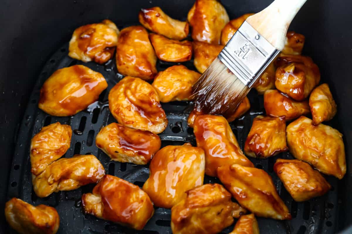 Overhead shot of someone smearing chicken with teriyaki sauce. 