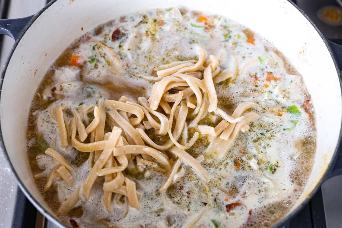 Overhead shot of noodles added in with the broth, chicken, bacon seasoning and veggies.