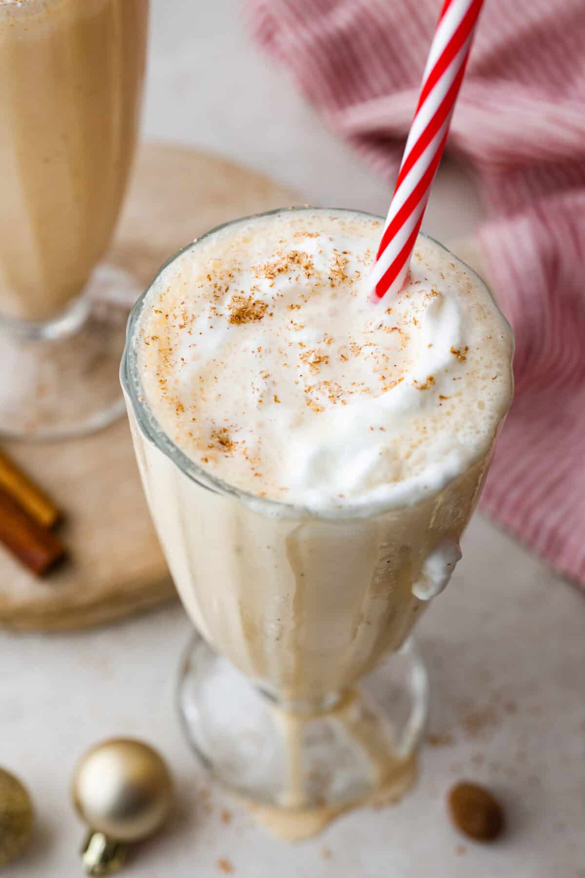 Angle shot of eggnog milkshake dripping down the sides of the glass.