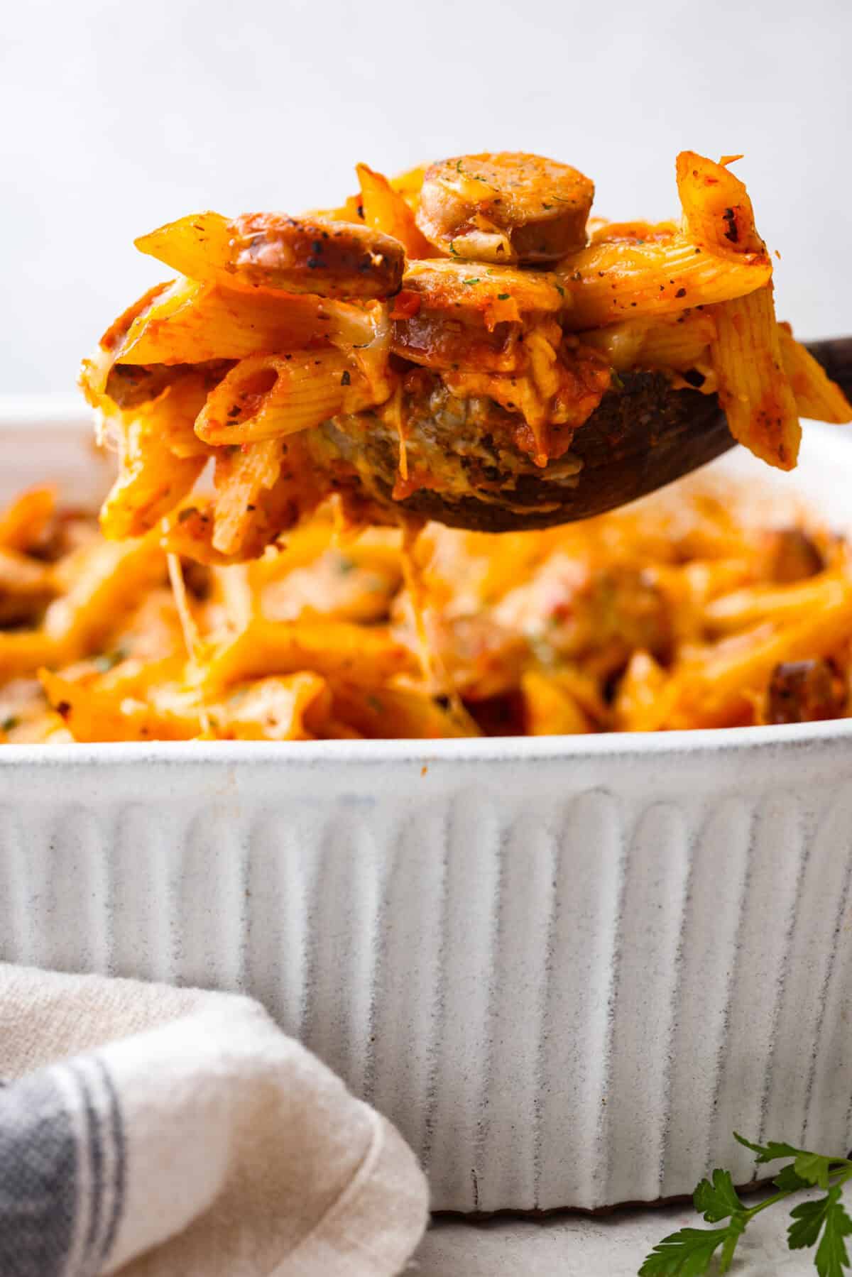 Side shot of someone lifting a scoop of Italian sausage casserole out of the dish.