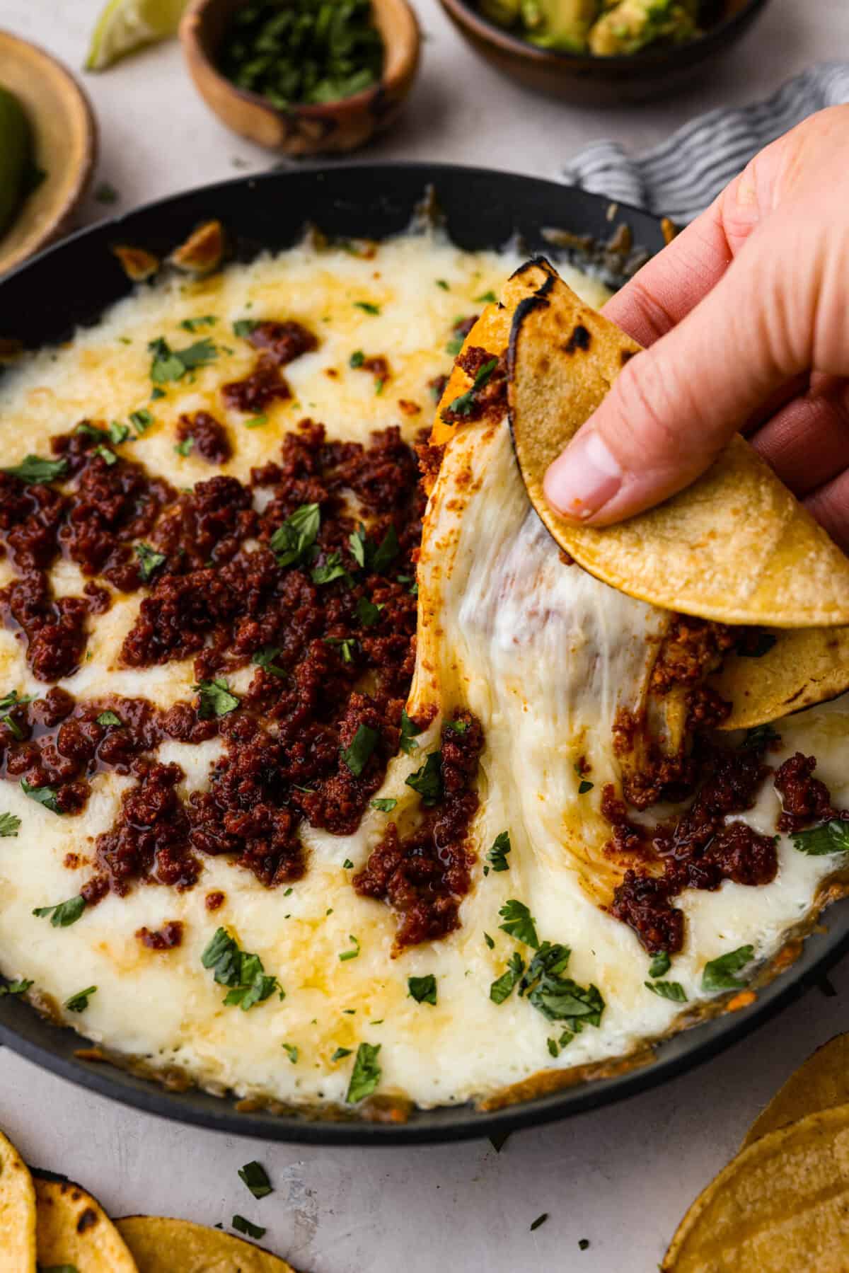 Close up shot of someone pulling up some queso fundido in a corn tortilla. 