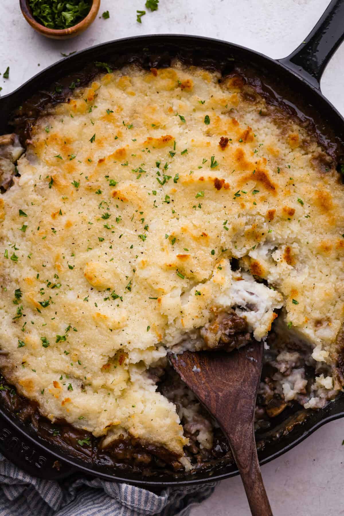 Overhead shot of salisbury steak casserole with a wooden serving spoon. 