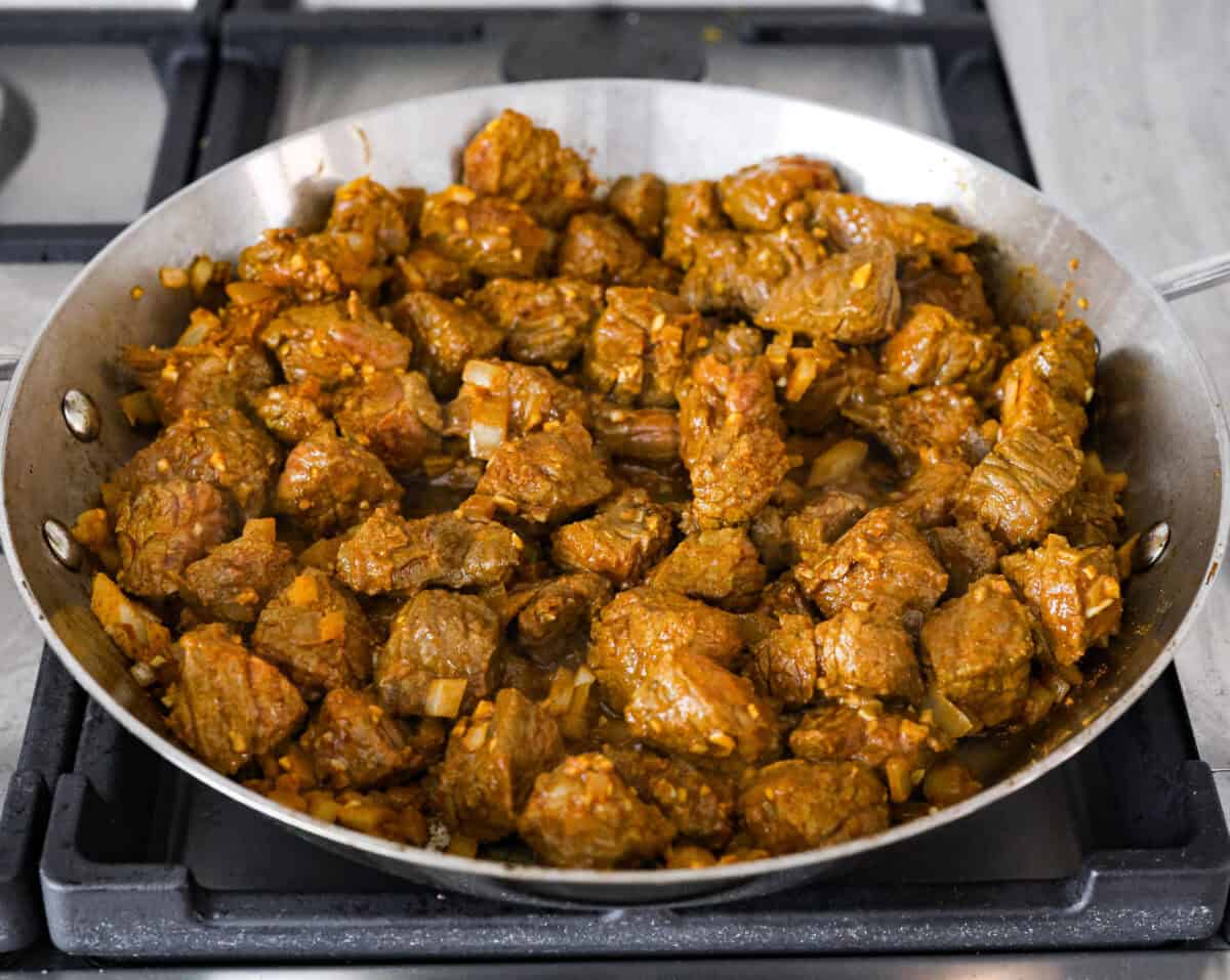 Angel shot of the beef and onion mixture cooking in a skillet on the stove 