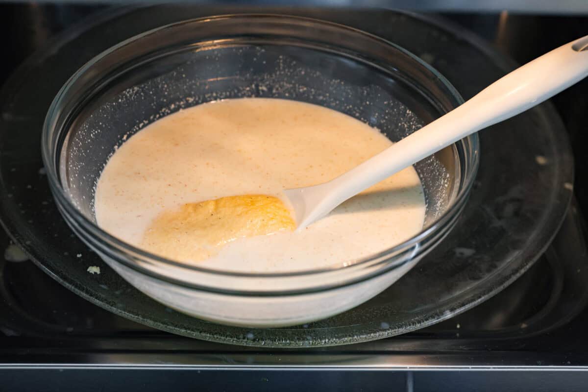 Angle shot of the bowl of milk and cornmeal in a bowl in the microwave. 