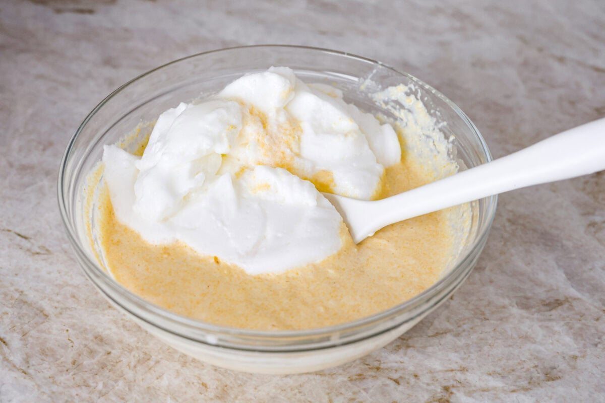 Angle shot of whipped egg whites being folded into the cornmeal mixture. 