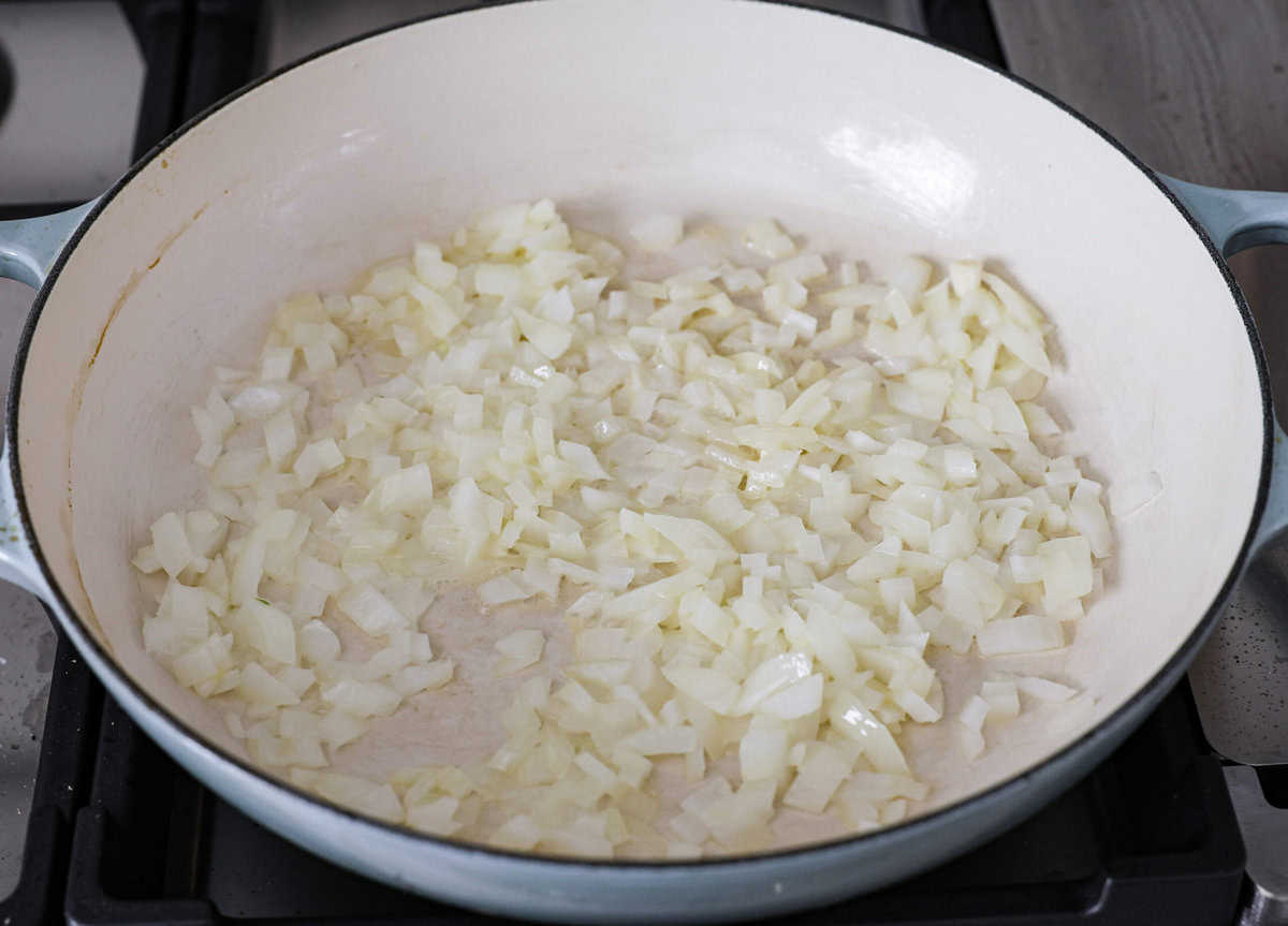 Chicken Pot Pie Pasta is a quick and easy twist on the classic comfort food. This one-pan recipe includes all the creamy, hearty flavors of a traditional chicken pot pie but swaps the pie crust for tender noodles. It’s a simple, fuss-free meal ready in just 30 minutes! Angle shot of onions sautéing in butter in a skillet.