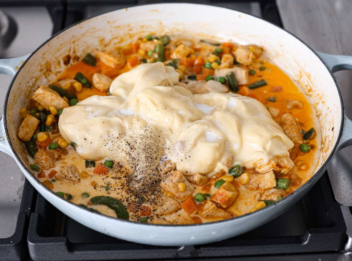 Chicken Pot Pie Pasta is a quick and easy twist on the classic comfort food. This one-pan recipe includes all the creamy, hearty flavors of a traditional chicken pot pie but swaps the pie crust for tender noodles. It’s a simple, fuss-free meal ready in just 30 minutes! Angle shot of the veggies added in with the chicken and onion mixture with milk, soup and salt and pepper over the top.