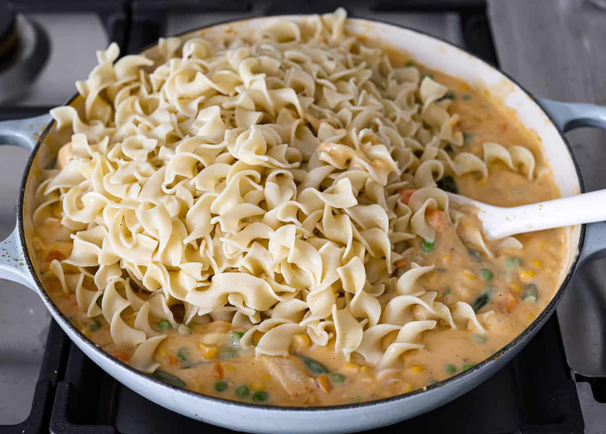 Chicken Pot Pie Pasta is a quick and easy twist on the classic comfort food. This one-pan recipe includes all the creamy, hearty flavors of a traditional chicken pot pie but swaps the pie crust for tender noodles. It’s a simple, fuss-free meal ready in just 30 minutes! Angle shot of all of the ingredients together in a skillet with the cooked noodles on top.