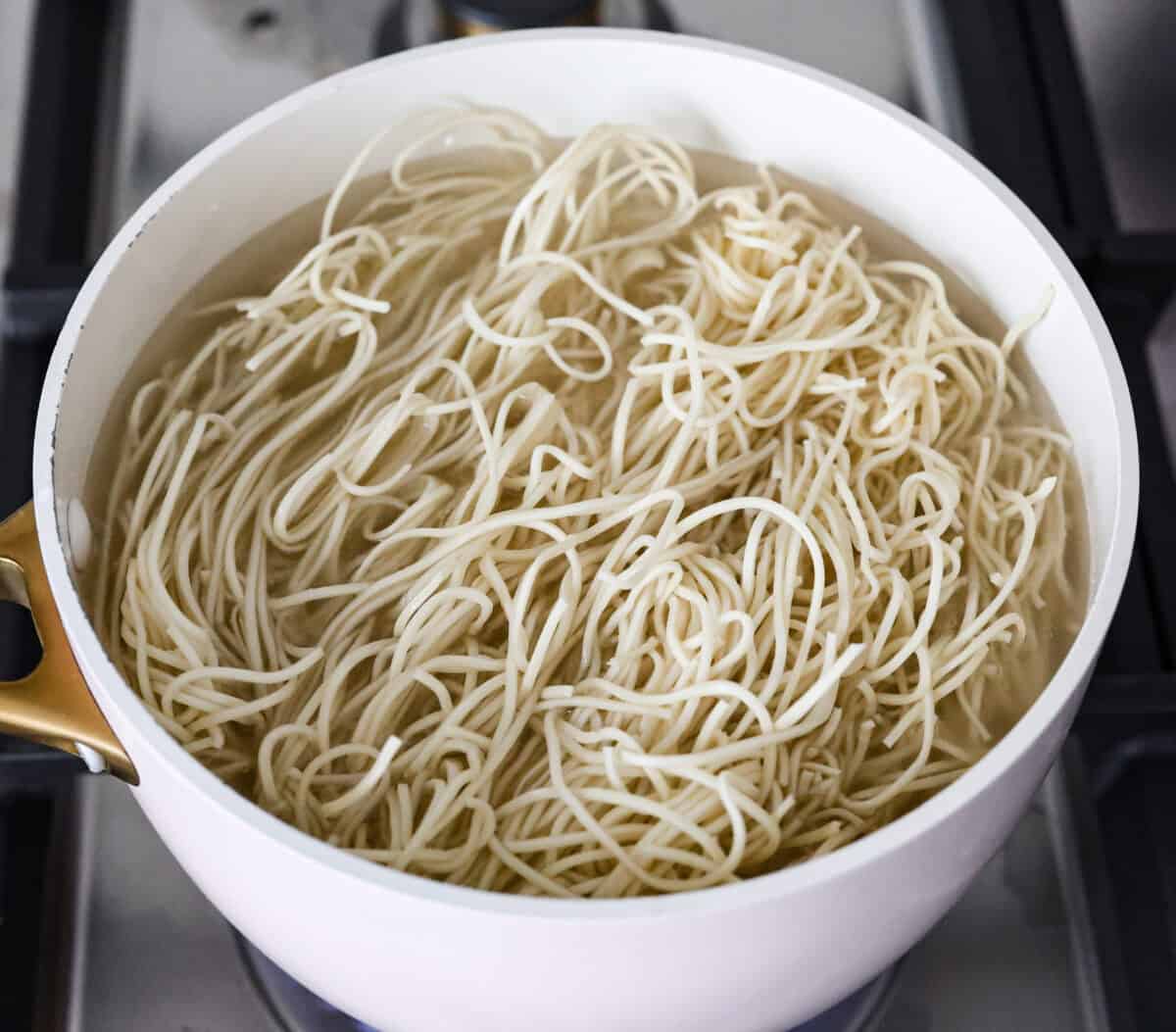 Overhead shot of low mein noodles cooking in a pot of water. 